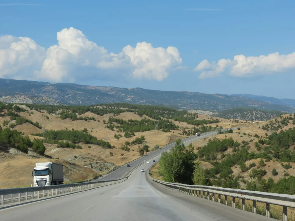 a truck driving down a road with mountains in the background